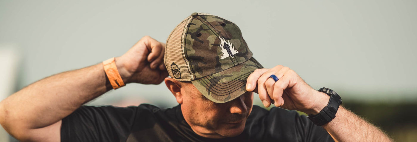 Man putting on a Tough Mudder by 47 OHT camo print hat
